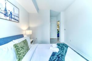 a white bedroom with a bed with two towels at RivetStays - The Jarvis in Toronto