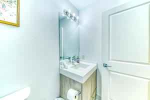 a white bathroom with a sink and a mirror at RivetStays - The Jarvis in Toronto