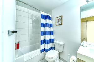 a white bathroom with a shower and a toilet at RivetStays - The Jarvis in Toronto