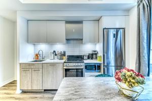 a kitchen with white appliances and a table with a vase of flowers at RivetStays - The Jarvis in Toronto