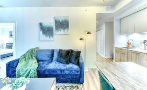 a living room with a blue couch and a kitchen at RivetStays - The Jarvis in Toronto