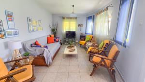 ein Wohnzimmer mit Couch und Stühlen in der Unterkunft Potidaia The Garden Oasis Summer House in Nea Potidaea