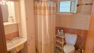 ein Bad mit einem Duschvorhang und einem WC in der Unterkunft Potidaia The Garden Oasis Summer House in Nea Potidaea + 21 Fotos
