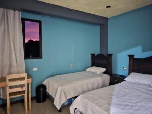 a bedroom with two beds and a blue wall at Hotel Amanecer Atitlán in San Juan La Laguna