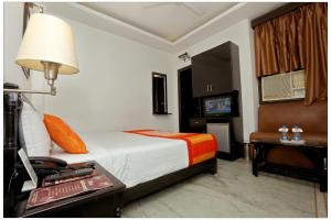 una camera d'albergo con letto e tavolo con lampada di Airport Hotel The R Blues - New Delhi a Nuova Delhi