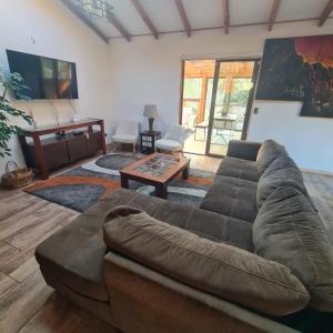 a living room with a couch and a table at CASA CON TINAJA, PISCINA Y QUINCHO - Pucón in Pucón