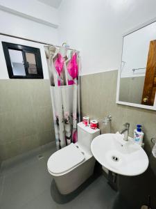 ein Badezimmer mit Toilette, Waschbecken und Spiegel in der Unterkunft Sammys House Rental in Puerto Galera