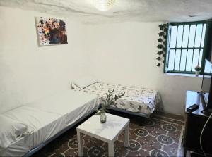 a small room with two beds and a table at Casa Cueva Puerta Verde in Paterna
