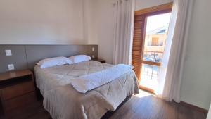a bedroom with a bed and a large window at Chalé Coração de Monte Verde in Monte Verde