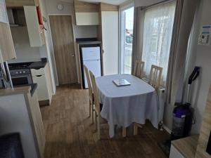 a small kitchen with a table and chairs in a room at PALM GROVE THE NeW PG68 3 BEDROOM CARAVAN CHAPEL ST LEONARDS in Chapel Saint Leonards +4 photos