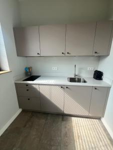 a kitchen with white cabinets and a sink at Duinpoort Appartement in Castricum +3 photos