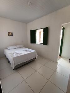 a white bedroom with a bed and two windows at hospedagem dos viajantes in Lençóis