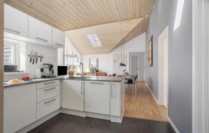 a kitchen with white cabinets and a wooden ceiling at Four-Bedroom Holiday Home In Rudkobing in Spodsbjerg