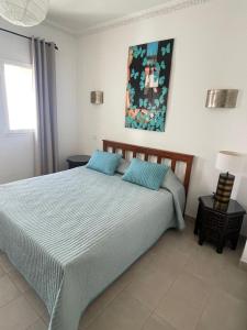 ein Schlafzimmer mit einem Bett und einem Gemälde an der Wand in der Unterkunft Les Jardins d'Assilah in Asilah