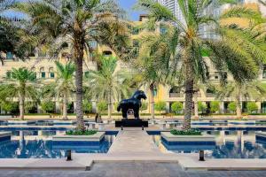 a horse statue in front of a building with palm trees at Dubai mall Aparment in Dubai