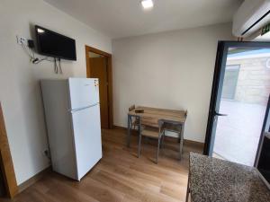 a kitchen with a refrigerator and a table with a television at Casa Alamela in Penafiel