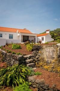 a house with a stone wall in front of a yard at Casa da Vigia in Calheta de Nesquim