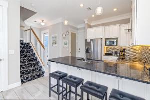 a kitchen with white cabinets and black counter stools at Two if by Sea in Mexico Beach