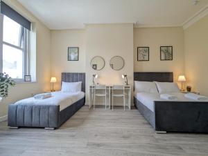 two beds in a room with a table and mirrors at Modern Apartment Near Manchester City Centre in Manchester