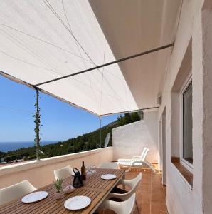 a wooden table with white chairs and an umbrella on a balcony at Apartmani "Nikola" Seaview - Ivan Dolac, Hvar in Ivan Dolac