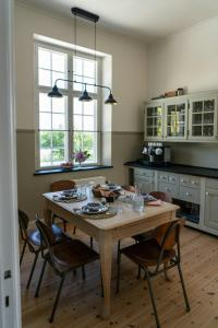 a kitchen with a wooden table with chairs and windows at Historic House In Skjoldungernes Land Park in Kirke Såby