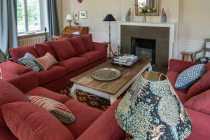 a living room with red couches and a fireplace at Historic House In Skjoldungernes Land Park in Kirke Såby