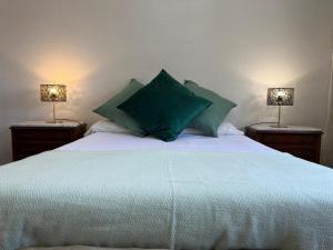 a bedroom with a bed with green pillows and two lamps at Ático en Santander Barrio Pesquero in Santander +5 photos