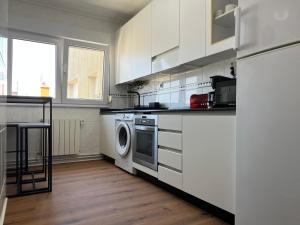 a kitchen with white cabinets and a washer and dryer at Ático en Santander Barrio Pesquero in Santander