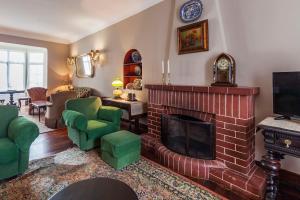 a living room with a fireplace and green chairs at Casa da Rua D'água in Ponta Delgada