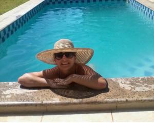 a woman in a straw hat sitting next to a swimming pool at Pousada Sítio Rústicu's in Domingos Martins