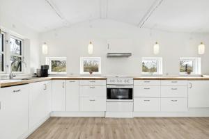 una cucina bianca con armadi bianchi e finestre di Bright Summer House With Pool In Tisvildeleje a Tisvildeleje