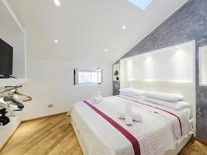a white bedroom with a large bed and a tv at HomeHolidaySanremo - Luxe & Glamour in Sanremo