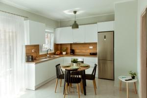 a kitchen with white cabinets and a table and chairs at Ammoshine Suite 1 in Nea Peramos