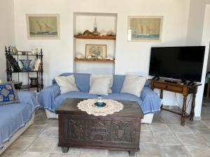 a living room with a blue couch and a tv at The Seashell House - Chora, Kythera in Kythira