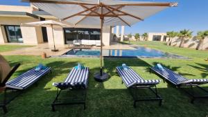 a group of lawn chairs with an umbrella and a pool at Villa Nisrine Your Private Oasis With Pool and No Overlooking in Marrakech
