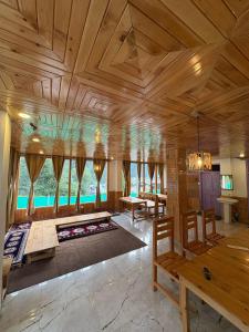 a large room with a wooden ceiling and tables and chairs at The Pahadi Soul Stay and Café in Jibhi