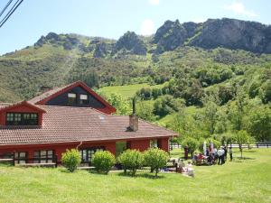 una casa en un campo con montañas al fondo en Hotel El Jisu, en Camaleño
