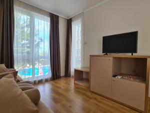 Una sala de estar con un televisor de pantalla plana y un sofá. en Messembria Palace, en Sunny Beach
