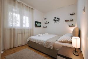 a white bedroom with a bed and a window at Apartman Vukota Pirot in Pirot