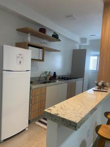 a kitchen with a white refrigerator and a counter at Apto Novo no Centro de Serra Negra com Garagem in Serra Negra