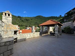 a patio with a stone wall and a gazebo at Villa Silentia in Lastovo