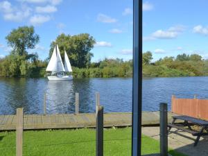 a sailboat on a river with a boat in the water at Pintail in Brundall