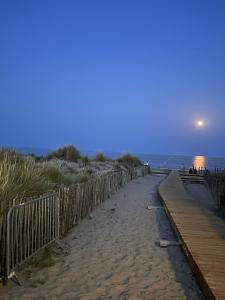une plage de sable avec une clôture et l'océan dans l'établissement Au balcon de la mer, appartement à Marseillan plage, à Marseillan