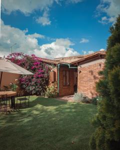 een huis met een tuin met een tafel en bloemen bij Cabaña en el casco urbano de Subachoque in Subachoque