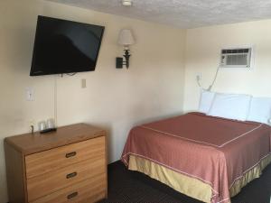 a hotel room with a bed and a flat screen tv at Caravan Motel in Niagara Falls
