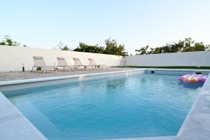 a swimming pool with chairs and a pool noodle in the water at Four Oaks Holiday House in Murvica