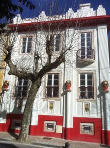 un edificio blanco y rojo con un árbol delante de él en Puzzle Suites B&B, en Figueira da Foz