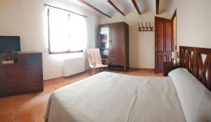 a bedroom with a bed and a dresser and a television at Casa Rural María in Los Alagones