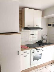 a kitchen with white cabinets and a stove at Évasion en bord de mer - T2 au coeur des calanques in Ensuès-la-Redonne