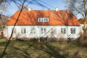 an old white house with an orange roof at Idyllic Kågården With Skovsgaard Nature Retreat in Rudkøbing